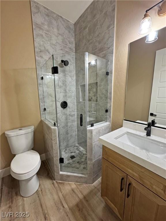 3080 S Prairie Ave, Pahrump, NV 89048 - bathroom featuring a stall shower, vanity, toilet, and wood finished floors