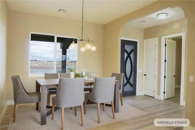 3080 S Prairie Ave, Pahrump, NV 89048 - dining space with arched walkways, a chandelier, light wood finished floors, and baseboards