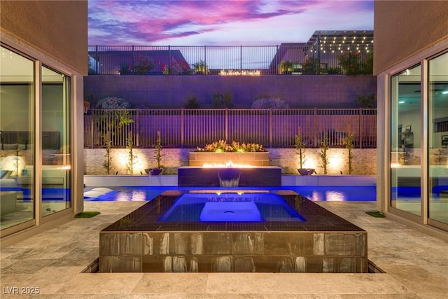 pool at dusk with an outdoor fire pit, a fenced backyard, a patio area, and an outdoor pool