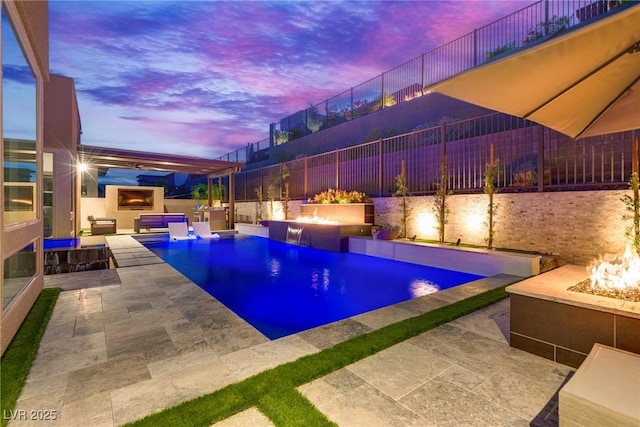 pool at dusk with a fire pit, a fenced in pool, a patio, fence, and exterior kitchen