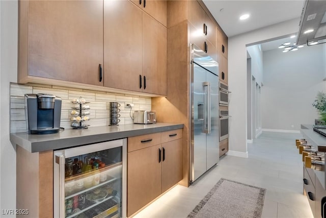 bar with wine cooler, stainless steel built in fridge, backsplash, and baseboards