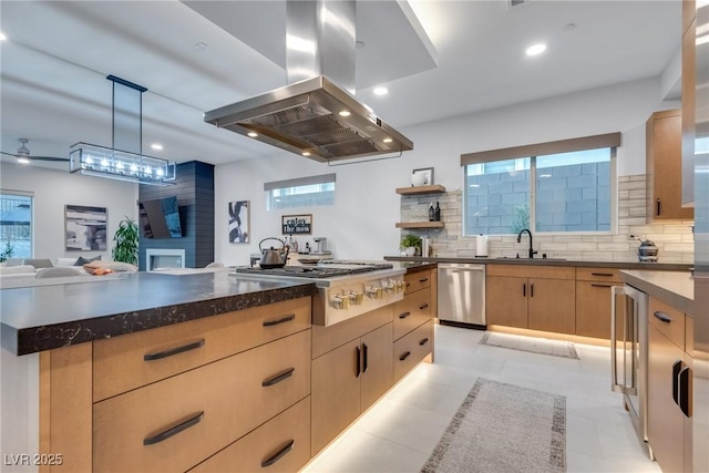 kitchen featuring light brown cabinets, a sink, appliances with stainless steel finishes, backsplash, and island exhaust hood