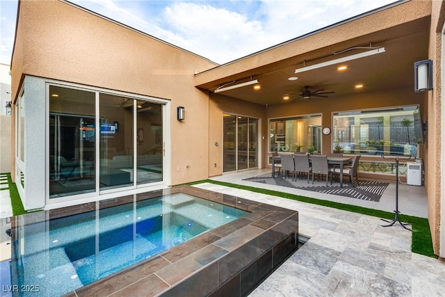 exterior space featuring a patio area, ceiling fan, an in ground hot tub, and stucco siding