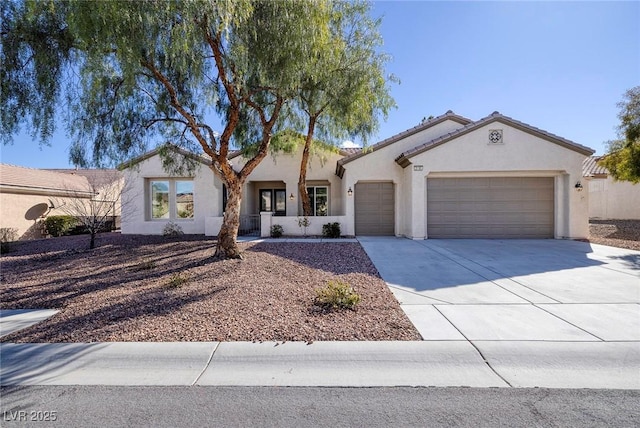 mediterranean / spanish house featuring concrete driveway, an attached garage, a tiled roof, and stucco siding