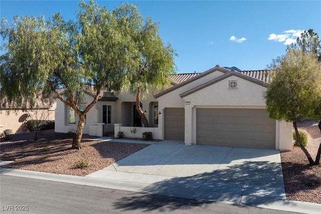 mediterranean / spanish house featuring driveway, an attached garage, a tiled roof, and stucco siding