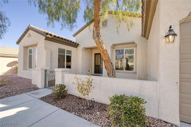 view of front of property featuring a fenced front yard, a tile roof, a gate, and stucco siding