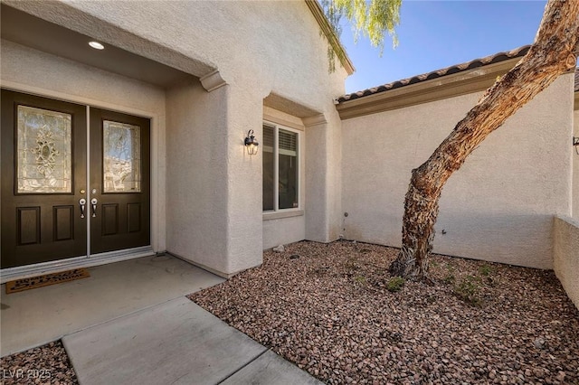 property entrance featuring french doors, a tiled roof, and stucco siding