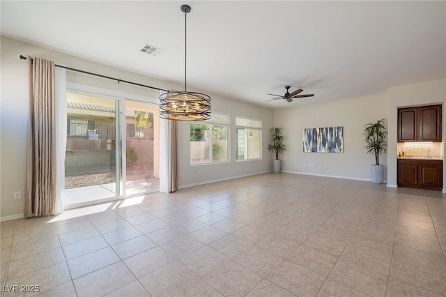 empty room featuring baseboards, visible vents, a ceiling fan, and light tile patterned flooring