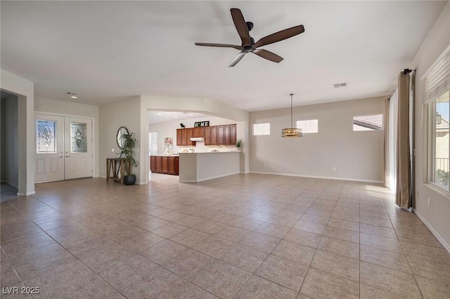 unfurnished living room with french doors, light tile patterned floors, visible vents, ceiling fan, and baseboards