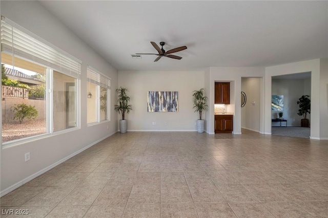 unfurnished living room featuring light tile patterned floors, a ceiling fan, visible vents, and baseboards