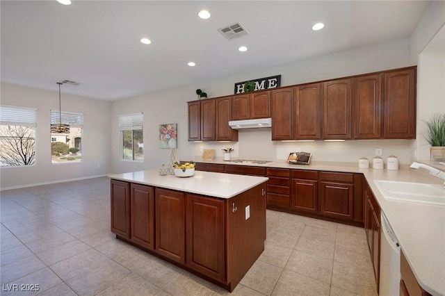 kitchen featuring light countertops, stainless steel gas stovetop, a sink, dishwasher, and under cabinet range hood