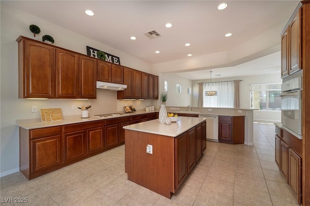 kitchen featuring light countertops, visible vents, a peninsula, white appliances, and under cabinet range hood