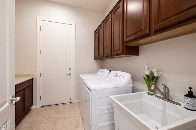 clothes washing area with cabinet space, light tile patterned flooring, a sink, and washing machine and clothes dryer