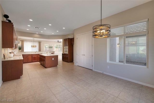 kitchen with baseboards, visible vents, white oven, light countertops, and pendant lighting