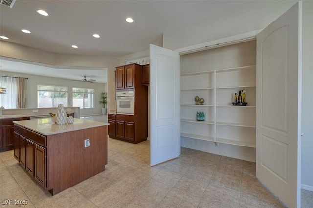 kitchen featuring recessed lighting, a sink, a kitchen island, light countertops, and white oven