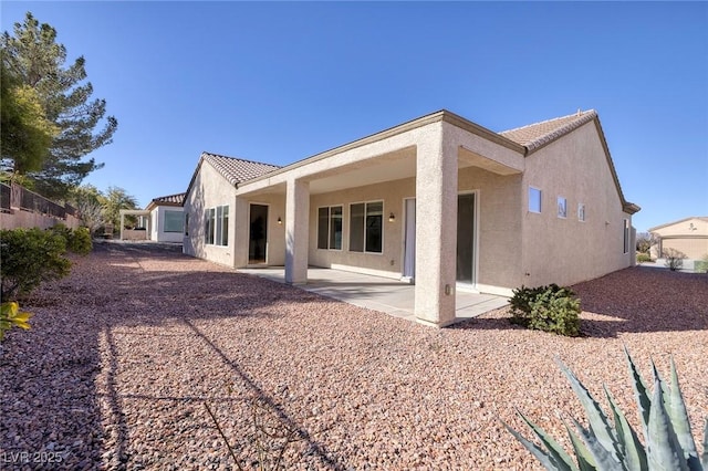 rear view of house featuring a tiled roof, a patio area, and stucco siding