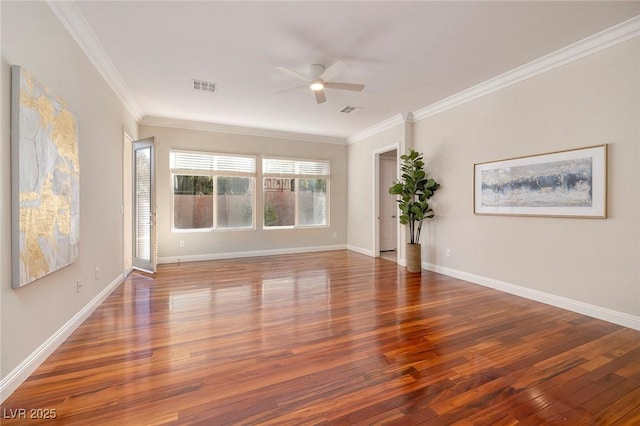 spare room with wood finished floors, visible vents, and crown molding