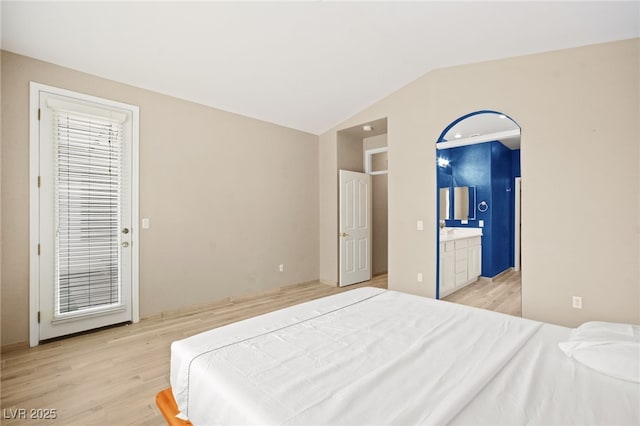 bedroom featuring connected bathroom, lofted ceiling, and light wood finished floors