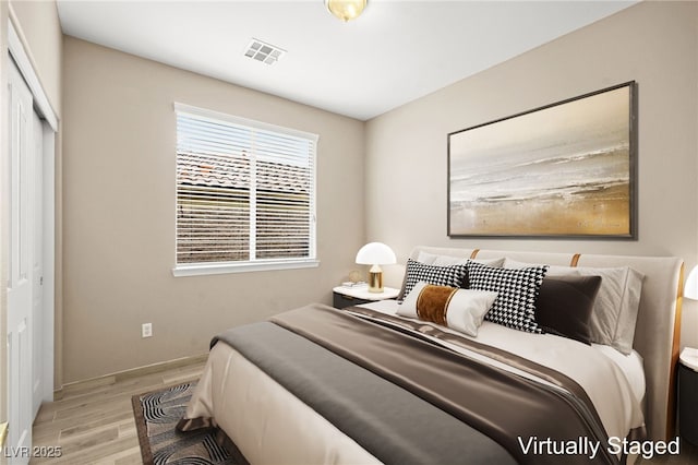 bedroom featuring wood finished floors, visible vents, a closet, and baseboards