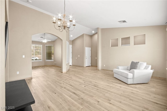 unfurnished room featuring light wood finished floors, visible vents, ceiling fan with notable chandelier, arched walkways, and high vaulted ceiling