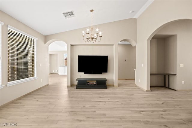 unfurnished living room featuring visible vents, lofted ceiling, light wood-style flooring, arched walkways, and a notable chandelier