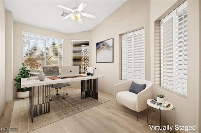 home office featuring a ceiling fan, wood finished floors, visible vents, baseboards, and vaulted ceiling