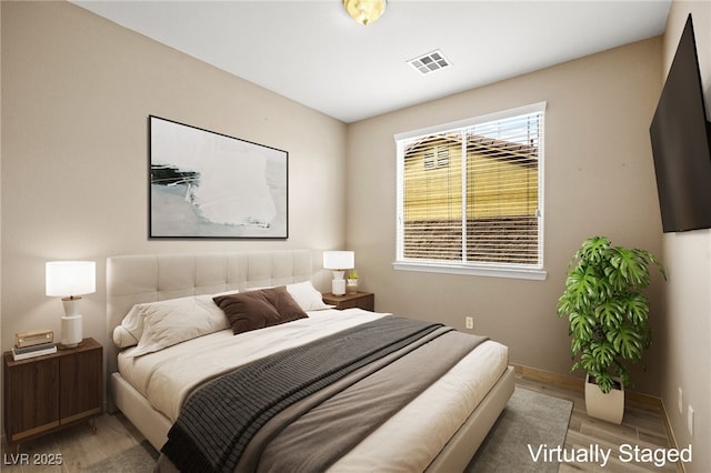 bedroom featuring visible vents, baseboards, and wood finished floors