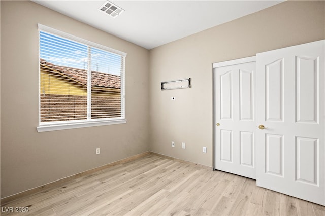 unfurnished bedroom featuring visible vents, light wood-style floors, and a closet