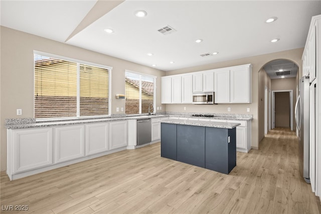 kitchen featuring arched walkways, visible vents, white cabinetry, and stainless steel appliances