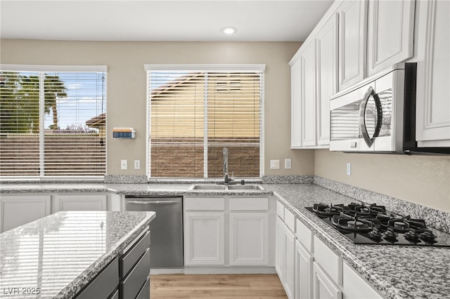 kitchen featuring light wood-type flooring, a sink, recessed lighting, appliances with stainless steel finishes, and white cabinets