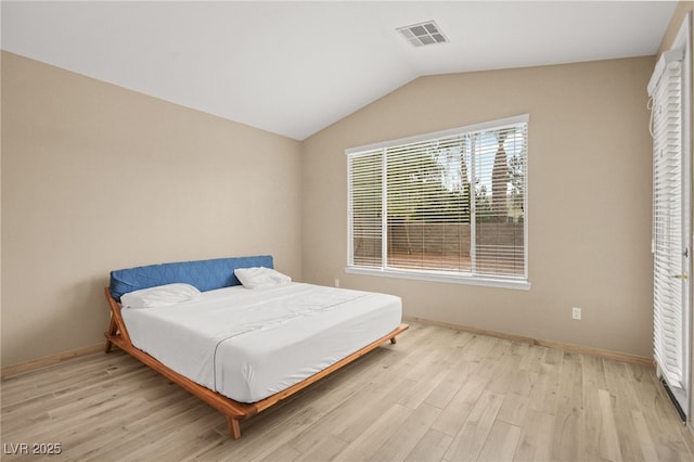 bedroom with light wood finished floors, visible vents, baseboards, and lofted ceiling