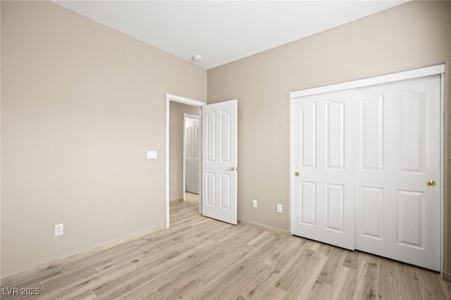 unfurnished bedroom featuring a closet, baseboards, and light wood-style floors