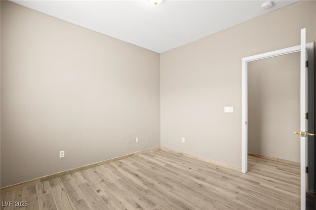 spare room featuring baseboards and light wood-style floors