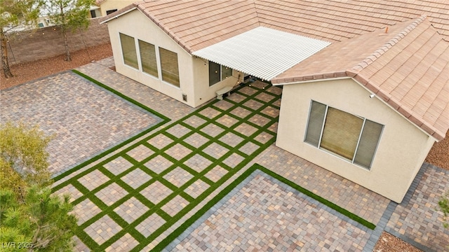 exterior space featuring a patio area, stucco siding, a tiled roof, and fence