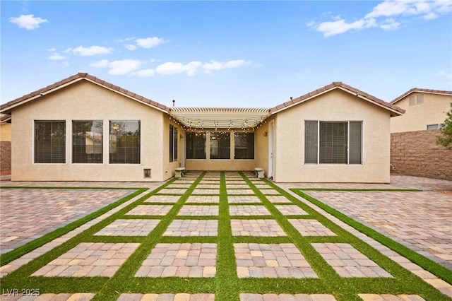 rear view of house with a patio, a tiled roof, and stucco siding