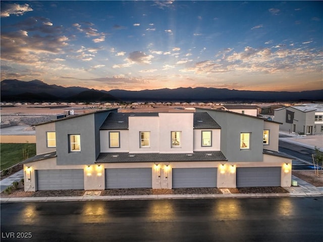 townhome / multi-family property with a garage, a mountain view, and stucco siding