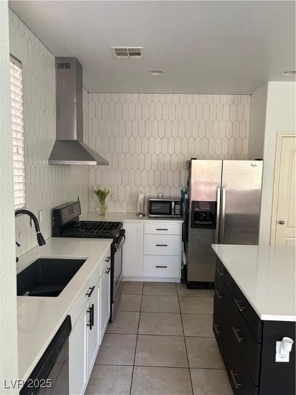 kitchen featuring visible vents, backsplash, wall chimney range hood, black appliances, and a sink