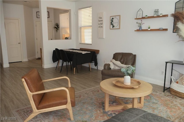 living area with baseboards and wood finished floors