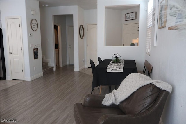 dining space with stairs, baseboards, and wood finished floors