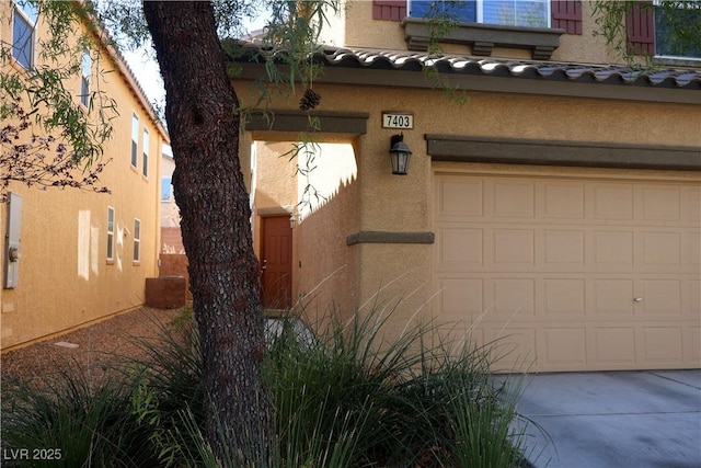 exterior space featuring stucco siding, an attached garage, and a tile roof