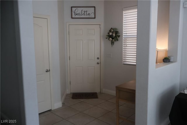 doorway featuring light tile patterned flooring and baseboards