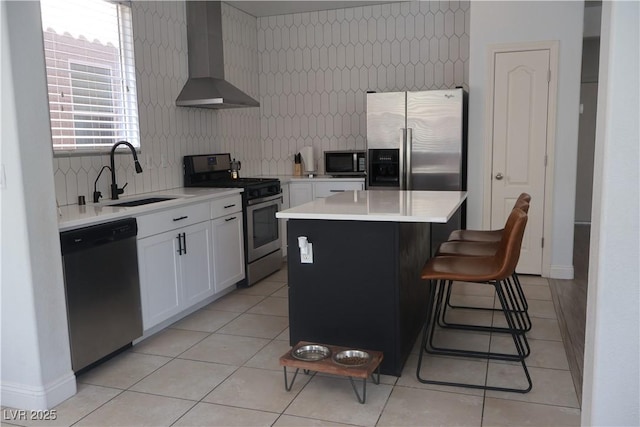 kitchen with a sink, decorative backsplash, light countertops, stainless steel appliances, and wall chimney exhaust hood