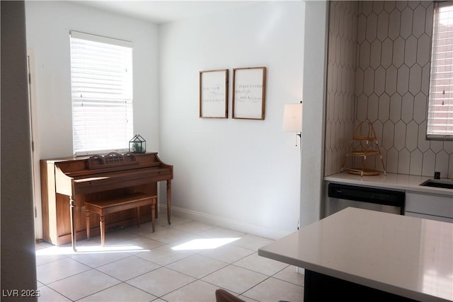 kitchen with tasteful backsplash, baseboards, light countertops, light tile patterned floors, and stainless steel dishwasher