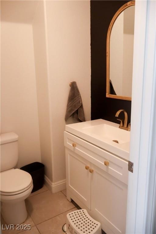 bathroom with baseboards, toilet, vanity, and tile patterned flooring