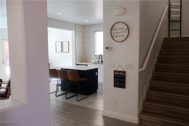 bar with stairway, baseboards, recessed lighting, a sink, and light wood-style floors