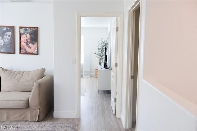 corridor with light wood-type flooring and baseboards