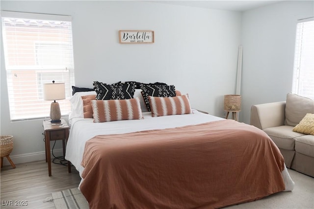 bedroom featuring light wood finished floors and baseboards