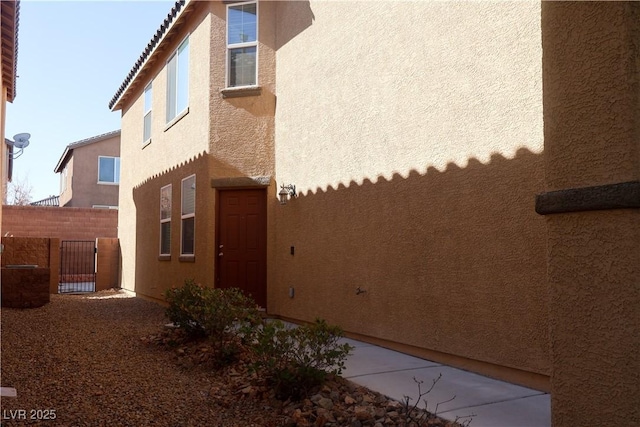 view of side of property featuring stucco siding and fence