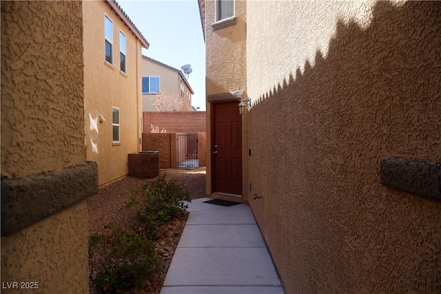 view of side of home featuring a gate, stucco siding, and fence