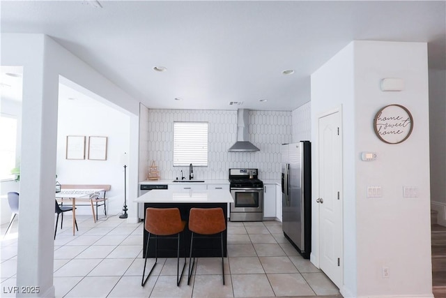 kitchen with light tile patterned floors, light countertops, stainless steel appliances, and wall chimney exhaust hood
